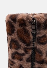Botki z sztucznego futra w kolorze brązowym z wzorem w panterę. Posiadają czarny zamek błyskawiczny i pluszową teksturę. Wysokość sięga do połowy łydki.