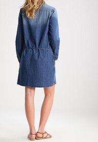 Kangashirtimekko keskisinisessä, pitkät hihat, kapea vyötärö, sivurei'ät ja hieman kaareva helma. Sileä rakenne, rento muotoilu.