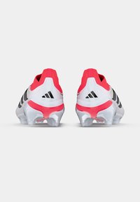 Λευκά ποδοσφαιρικά παπούτσια με ροζ λεπτομέρειες, μαύρες ρίγες και διάφανα πέλματα. Διαθέτουν επενδεδυμένο κολάρο και υλικό με υφή για υποστήριξη.