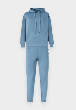 Ensemble de survêtement bleu clair en deux pièces avec sweat à capuche doté d'une poche avant et pantalon assorti à coupe fuselée.