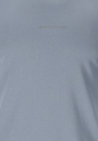 Surface en tissu gris clair avec un texte en relief subtil "ENDURANCE" centré près du haut.