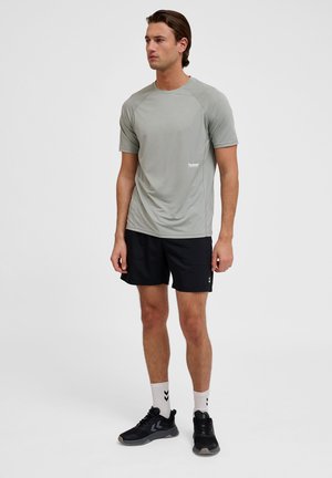 Lichtgrijs sportshirt met korte mouwen en een ronde halslijn, gecombineerd met zwarte shorts en zwarte sneakers met grijze accenten.