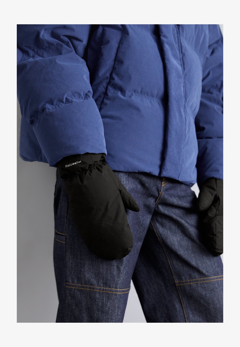 Czarne rękawice z elastycznymi mankietami na nadgarstkach, noszone z niebieską kurtką puchową. Rękawice mają logo, a strój uzupełniają ciemne dżinsy.