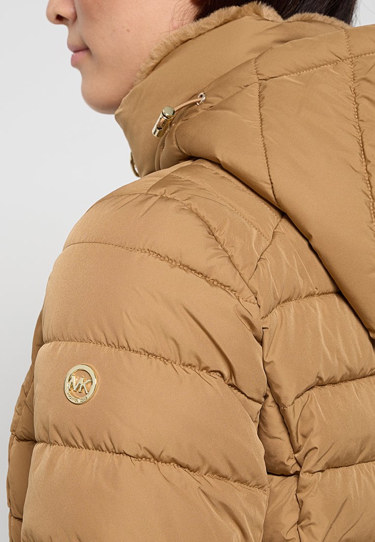 Braune Steppjacke mit abnehmbarem Kapuze, goldenen Beschlägen und einem Logo-Patch am Ärmel. Glatte Textur mit gestepptem Muster.