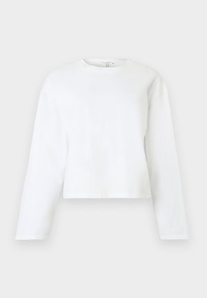 Crop top blanc à manches longues en coton doux. Dispose d'un col rond et d'un ourlet droit. Design simple et minimaliste sans motifs.