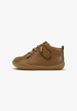 Scarpa da bambino in pelle marrone con punta arrotondata, suola morbida, chiusura frontale con lacci e cinturino in velcro con etichetta Camper su sfondo bianco.