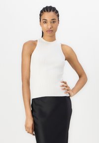 Top bianco a collo alto con una silhouette aderente, abbinato a una gonna nera in satin. Tessuto liscio, design minimalista e senza motivi visibili.