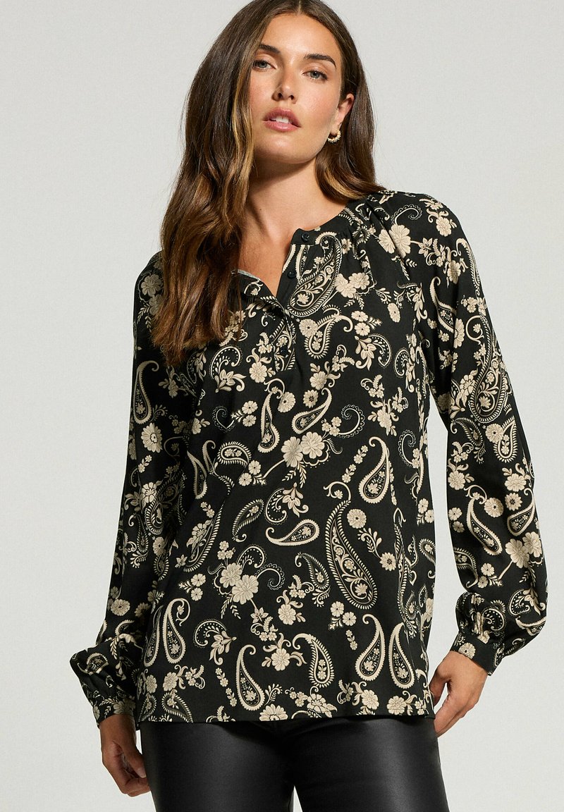 Schwarze Bluse mit floralen und Paisleymustern in Creme, langen Ärmeln mit gerafften Manschetten und einem durch Knöpfe geschlossenen Henley-Ausschnitt.