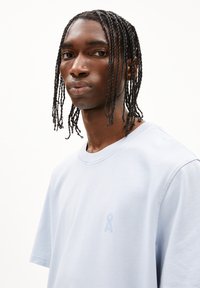 Lichtblauw katoenen T-shirt met korte mouwen, ronde halslijn en een klein tonale logo op de borst. Soepele textuur en een relaxte pasvorm.