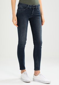 Smalle jeans i mörkblå denim med en slät textur, som har en klassisk femfickdesign och lätt blekning på låren.