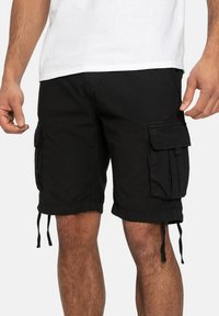 Homme portant un short cargo noir avec des poches à rabat et des cordons, associé à un t-shirt blanc uni.