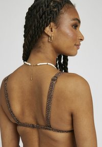 Soutien-gorge de bikini à imprimé léopard avec bretelles réglables, texture de tissu lisse et fermeture à agrafe à l'arrière. Doté de jolis accents en métal doré.
