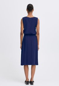 Navy blue sleeveless dress with a gathered elastic waist, flowing knee-length skirt, and smooth fabric texture. Simple design, no patterns.