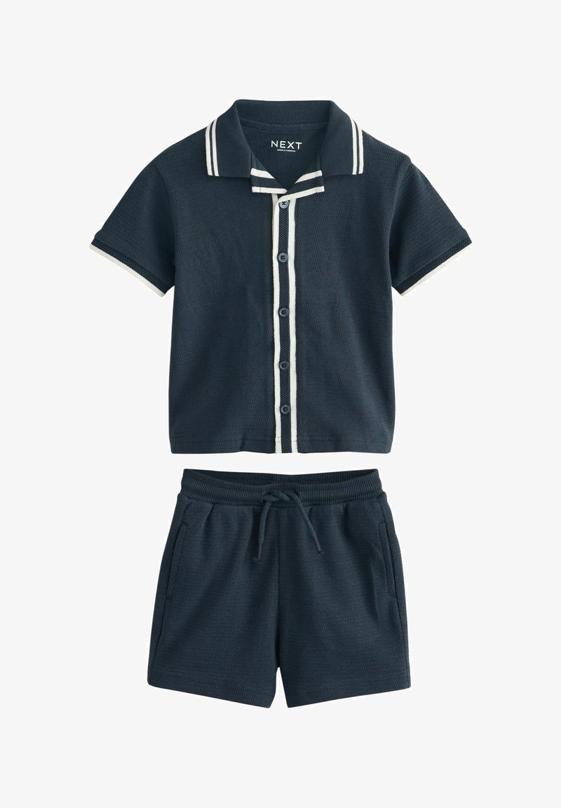 Granatowy zestaw koszulek polo z krótkim rękawem i spodenek, z białymi paskami na kołnierzyku i rękawach, z przodu zapinany na guziki, z elastycznym pasem i sznurkiem do regulacji.