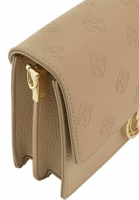 Beżowa skórzana torebka z wytłaczanym wzorem, z elementami z mosiądzu w kolorze złotym i teksturowanymi bokami. Posiada sztywną konstrukcję z klapą.