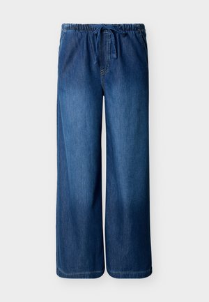 Φαρδιά μπλε τζιν παντελόνια με ελαστική μέση και κορδόνι σε απλό ανοιχτό φόντο.