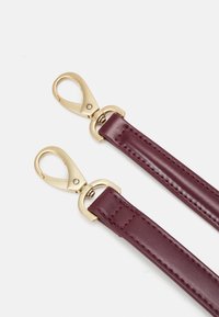 Burgundy läderrem med guldfärgade metallkarbinhakar och sömdekor. Har en slät yta och en platt design.