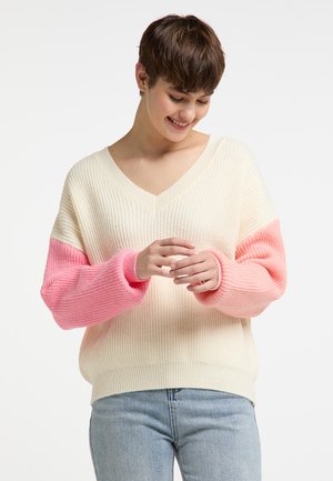 Pull à col en V couleur crème avec des manches dégradées roses, texture côtelée et coupe ample. Présente des couleurs contrastantes et des poignets décontractés.