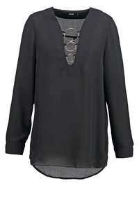 Blusa nera a maniche lunghe con scollatura a V e dettagli metallici circolari al centro. Tessuto morbido con orlo curvo.