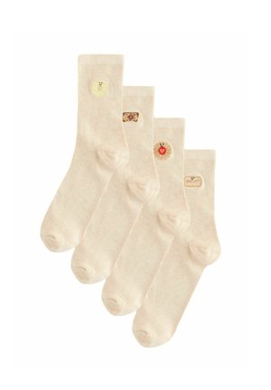 Vier beige sokken met kleine geborduurde patches van een glimlachende citroen, een koekje, een zon met een hart en een koekjeslabel op de enkels.
