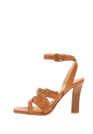 Sandalo con tacco alto in pelle color cuoio con tre cinturini, due con fibbie color oro, e tacco a blocco in legno impilato.