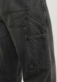 Svarta jeans med flera fickor, med en strukturerad tyg, synliga sömmar och en avsmalnande passform. Hållbar och praktisk design.