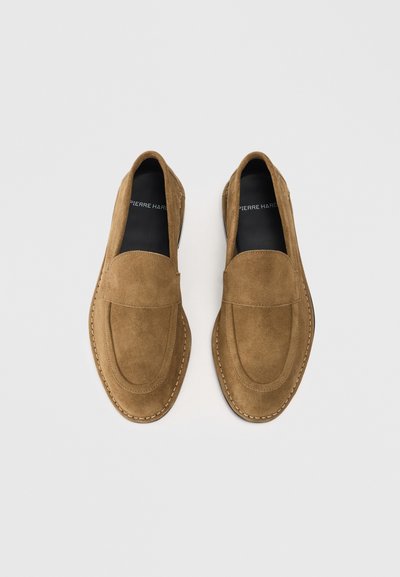 Brune ruskinds loafers med en glat finish, rund tå og dekorativ syning. Indvendigt er de forsynet med sort foring med branding.