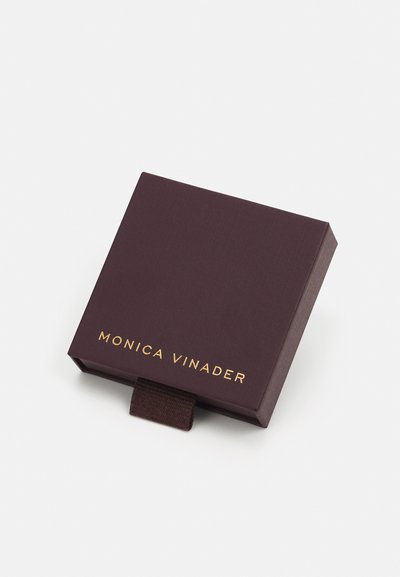 Sams burgundijas krāsas kartona rotaslietu kaste ar strukturētu apdari, kurai ir zelta iespiešana "MONICA VINADER" un mīksts vilkšanas cilpiņa.