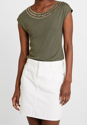 Haut vert olive à manches courtes avec un col décoratif en perles, associé à une jupe en denim blanche avec une fermeture à boutons sur le devant et des poches.