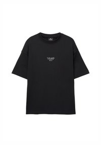 T-shirt nera a maniche corte con testo bianco "Nel bel mezzo del nulla" centrato sul petto, colletto arrotondato e vestibilità ampia.