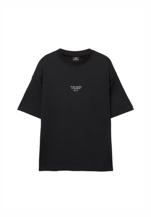 T-shirt noir à manches courtes avec le texte blanc "Au milieu de nulle part" centré sur la poitrine, col rond et coupe ample.