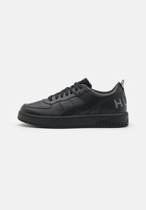 Baskets basses en cuir noir avec lacets noirs, semelle texturée et texte de marque "HUGO" sur le contrefort du talon.