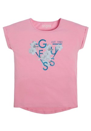 Pink kortærmet T-shirt med blå glitrende mærkenavn "GUESS,", hvidt blomsterprint og "EST. 1981" tekst på forsiden.