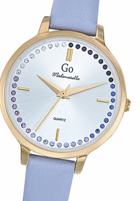 Montre en quartz dorée avec un cadran argenté ornée de strass bleus et violets, sur un bracelet en cuir bleu clair. Indices des heures simples.