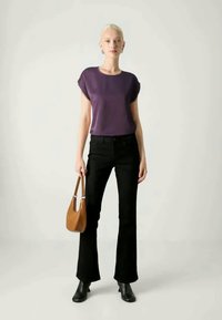 Camiseta roxa de mangas curtas, jeans pretos com corte flare, botas pretas de tornozelo e uma mala de ombro castanha. Design simples com texturas suaves.