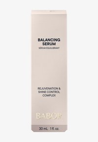 Verpakking van het serum in lichtbeige, rechthoekig ontwerp. Bevat zwarte tekst en gouden accenten. Bevat 30 ml verjongend serum.