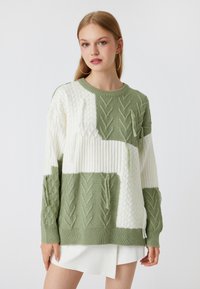 Grüner und weißer Kabelstrickpullover mit Blockmuster, ausgestattet mit gerippten Bündchen und Saum, strukturierten Details und rundem Halsausschnitt.