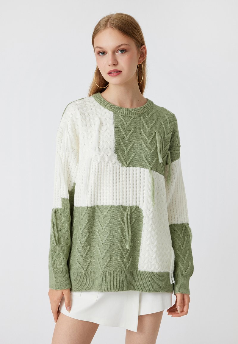 Grüner und weißer Kabelstrickpullover mit Blockmuster, ausgestattet mit gerippten Bündchen und Saum, strukturierten Details und rundem Halsausschnitt.