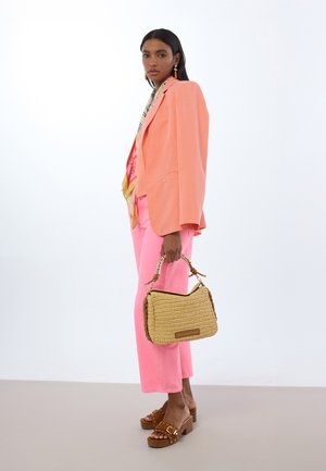 Blazer coral, pantalones anchos rosas, sandalias de plataforma marrones, bolso de paja tejido con asa trenzada y adorno decorativo.