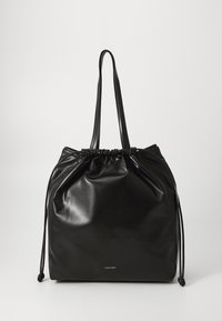 Borsa a tracolla nera con coulisse realizzata in materiale lucido. Presenta manici lunghi e un logo Calvin Klein ben visibile in basso. Design semplice.