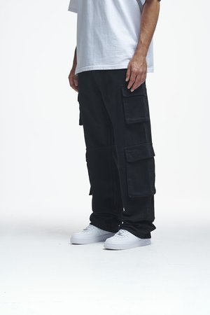 Black cargo pants made of cotton, featuring multiple side pockets and a relaxed fit. Paired with white sneakers and a loose-fitting white t-shirt.