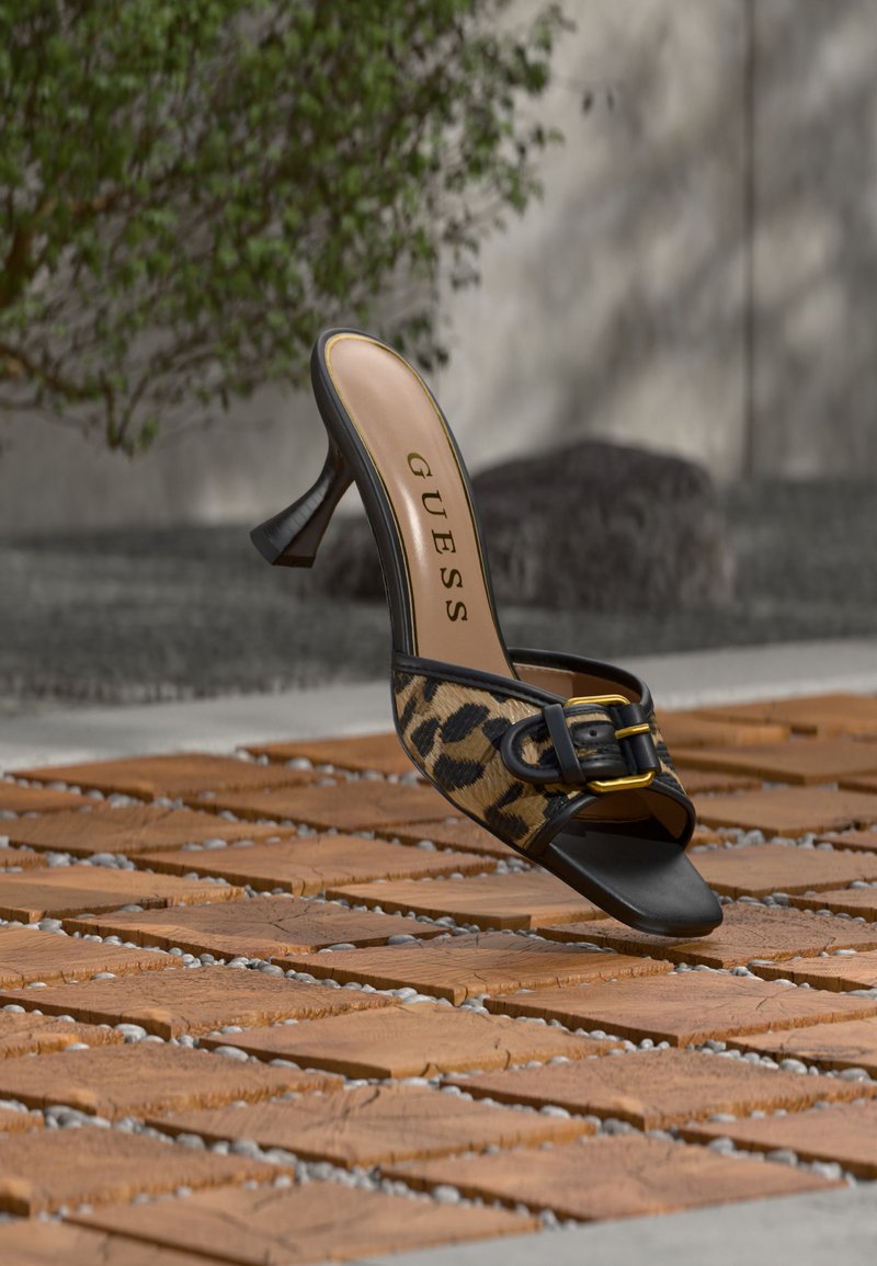 Μαύρη mule με λεοπάρ σχέδιο, τετράγωνη μύτη και χρυσή αγκράφα πάνω σε ξύλινο δάπεδο σε εξωτερικό χώρο.