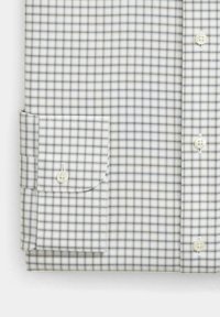 Camicia da uomo con bottoni di colore bianco, decorata con un motivo a quadri blu e nero, dotata di maniche lunghe e polsini regolabili con bottoni bianchi.