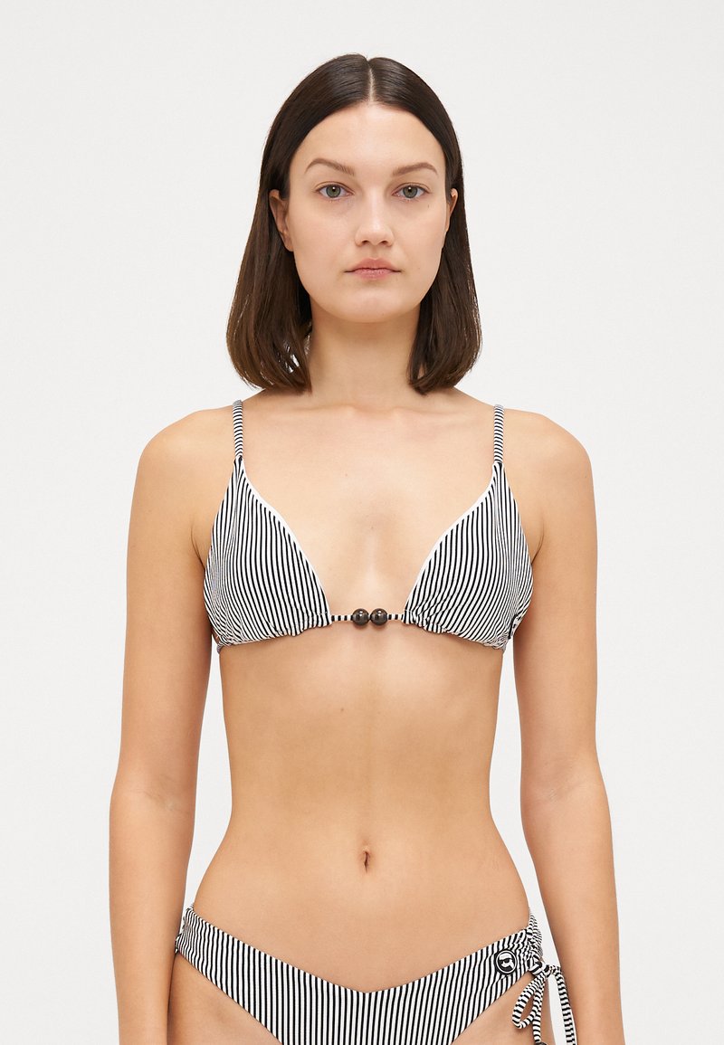 Bikini a righe bianche e nere con coppe triangolari, spalline regolabili e perline decorative al centro. Lacci sui lati del slip.