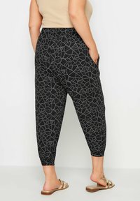 Svarta mönstrade joggerbyxor med lös passform, försedda med en geometrisk design och elastiska avslut. Inkluderar sidofickor för bekvämlighet.