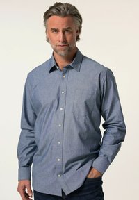 Camicia azzurra con bottoni realizzata in tessuto leggero, con taschino sul lato sinistro e maniche lunghe con polsini abbottonati.