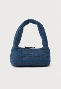 Blå quiltad handväska med vadderat handtag, dragkedjestängning och upprepat subtilt "tommy jeans"-textmönster samt metallogotyp framför.