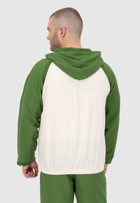 Giacca verde e bianca con zip e cappuccio, polsini e vita elasticizzati. Tessuto liscio con un design a blocchi di colore e maniche a contrasto.