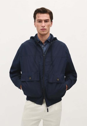 Marineblauwe hoodie in lichte stof, met twee knoopzakken op de borst, elastische manchetten en een ritssluiting aan de voorkant.