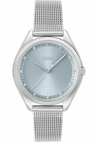 Reloj con correa de malla plateada y esfera de color azul claro, que presenta un acabado cepillado y marcadores de horas de cristal, además de una caja pulida en tono plateado.